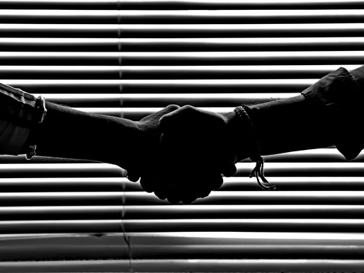 A handshake silhouette in front of some blinds