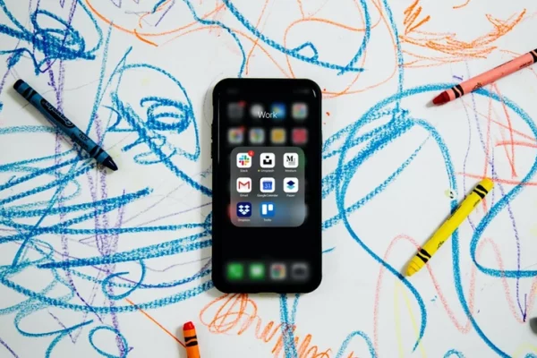 An iPhone on paper with crayons and scribbles