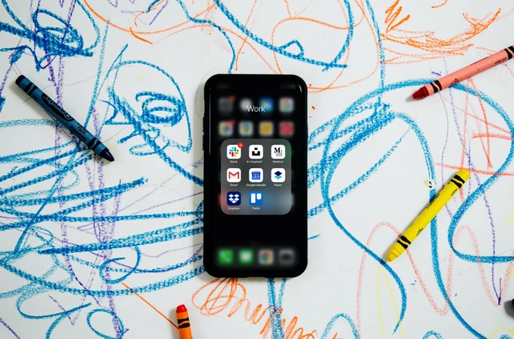 An iPhone on paper with crayons and scribbles