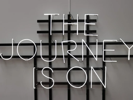 A neon wall sign that says The Journey Is On