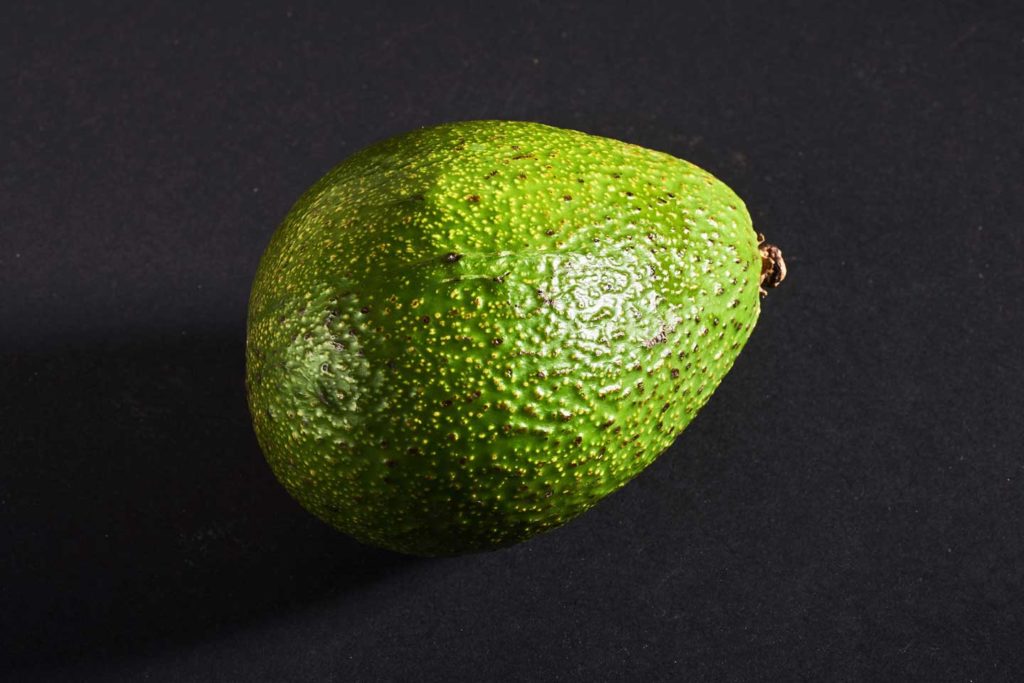 An avocado against black background