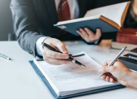 Close up of two peoples hands holding pens over document