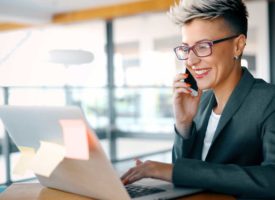 A business woman smiling and holding a phone